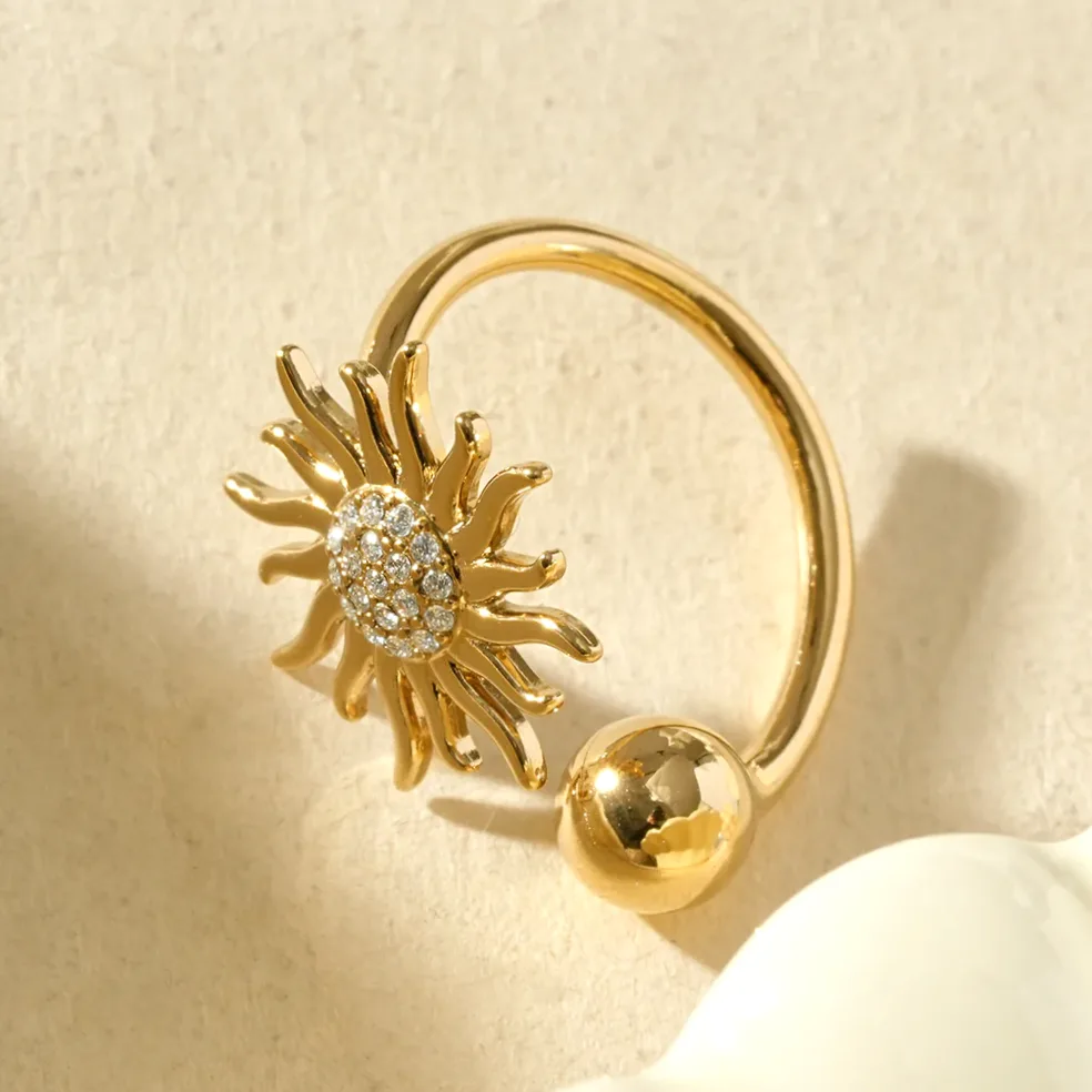 Detalle del material y acabado — Anillo dorado abierto sol brillante y esfera