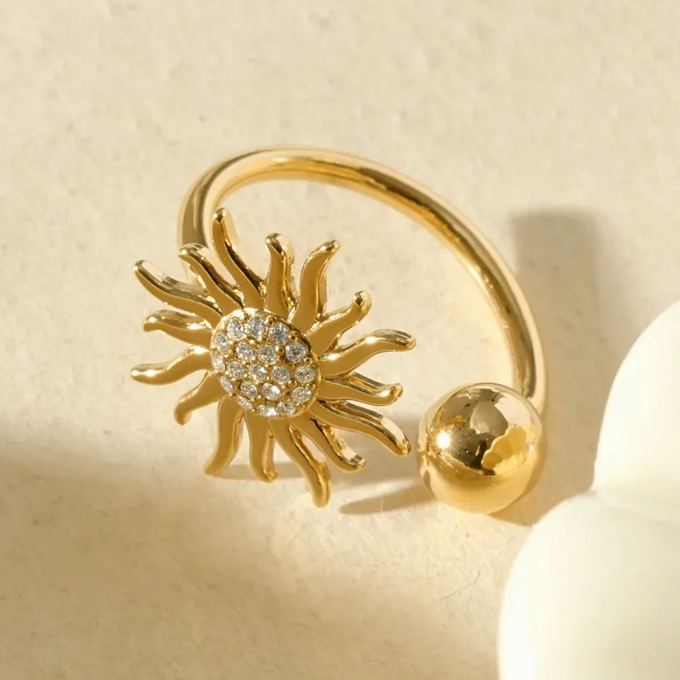 Anillo dorado abierto sol brillante y esfera puesto en el dedo
