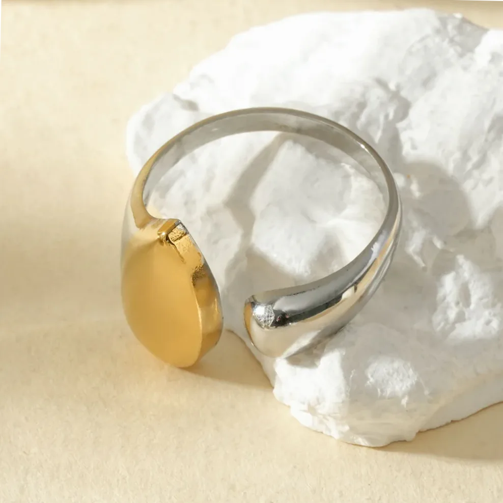 Anillo abierto delantero plateado con gota dorada puesto en el dedo