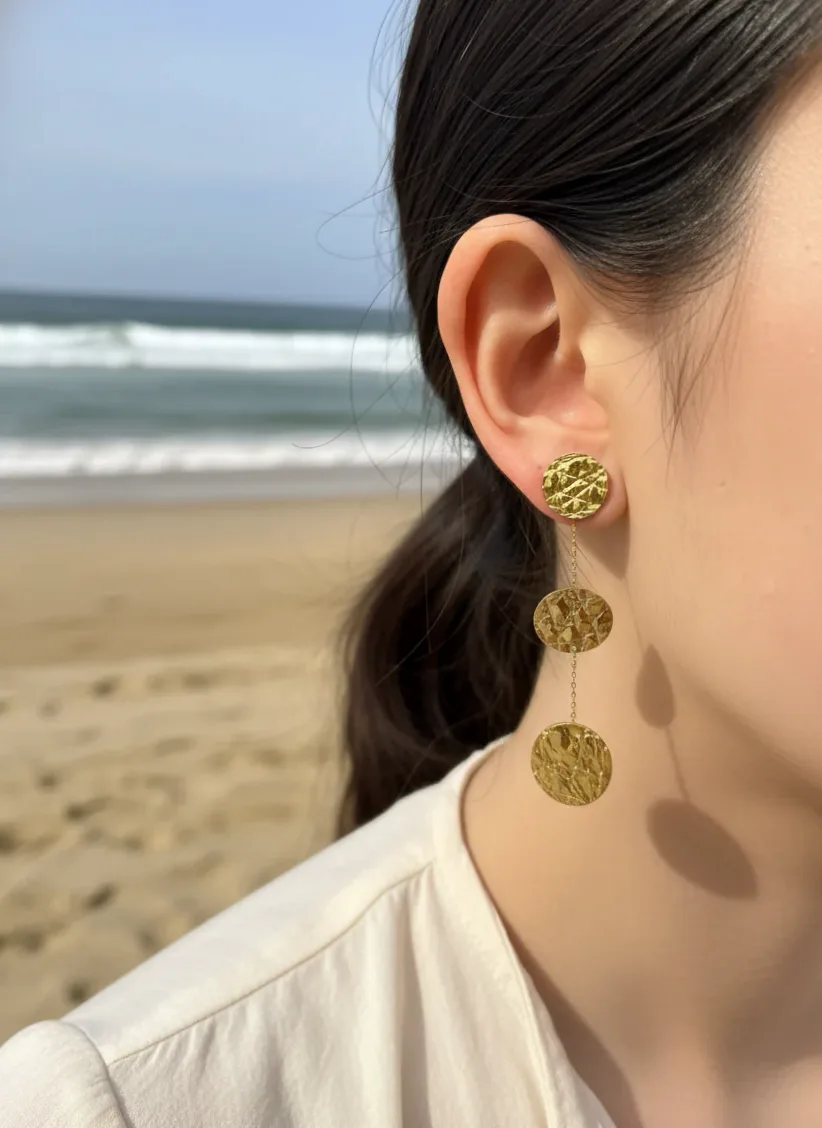 Detalhe do material e do acabamento — Brincos dourados pendentes pastilhas marteladas modernas