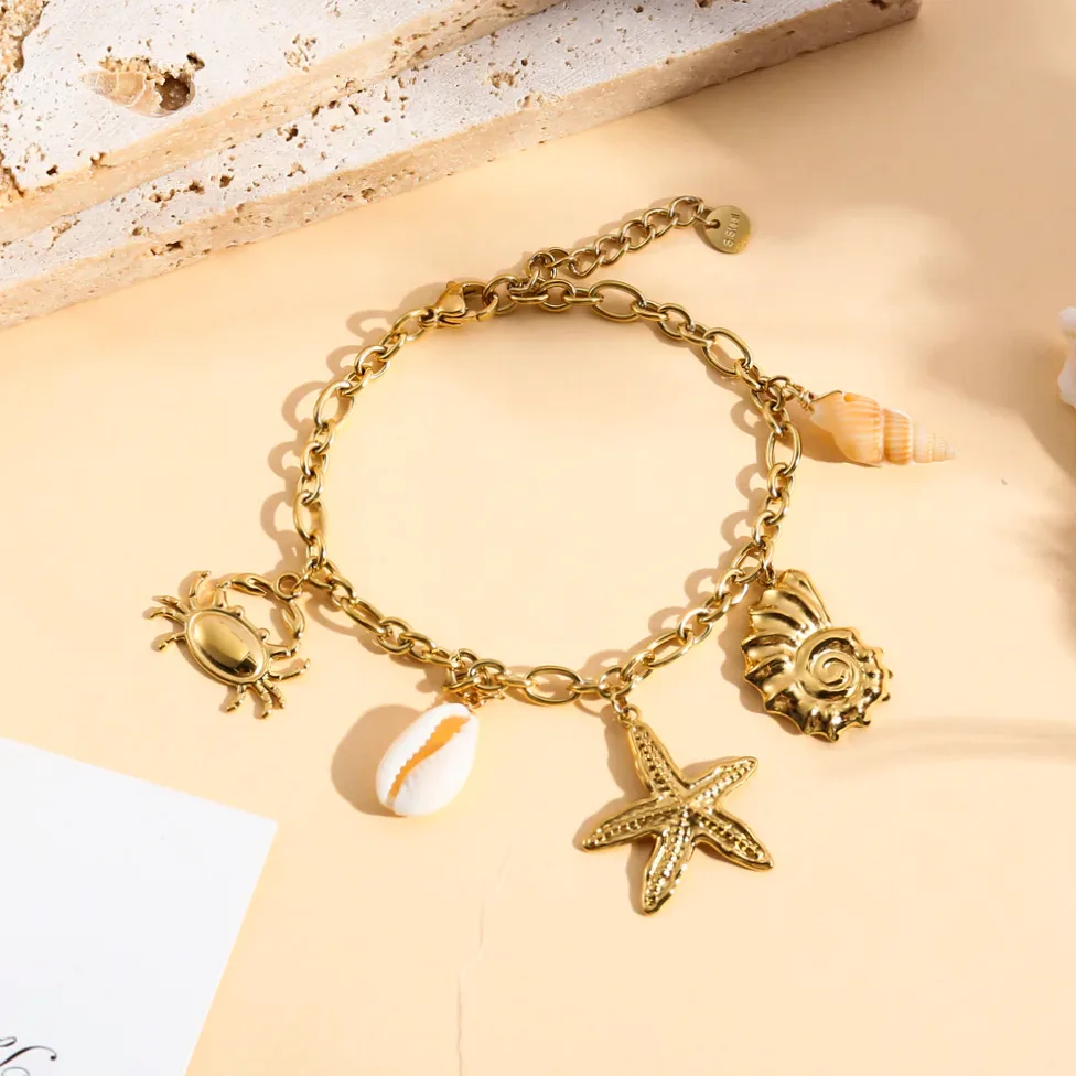 Detalhe do material e do acabamento — Pulseira dourada charms concha, estrela do mar e caranguejo