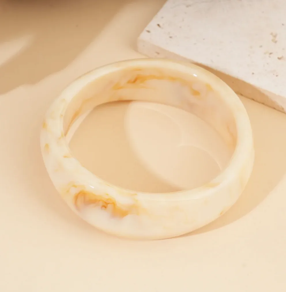 Pulsera rígida resina beige forma redonda moderna puesto en el tobillo