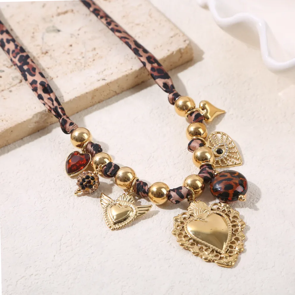Dettaglio del materiale e della finitura — Collana sfere dorate larga decorata tessuto leopardato charms cuore grande