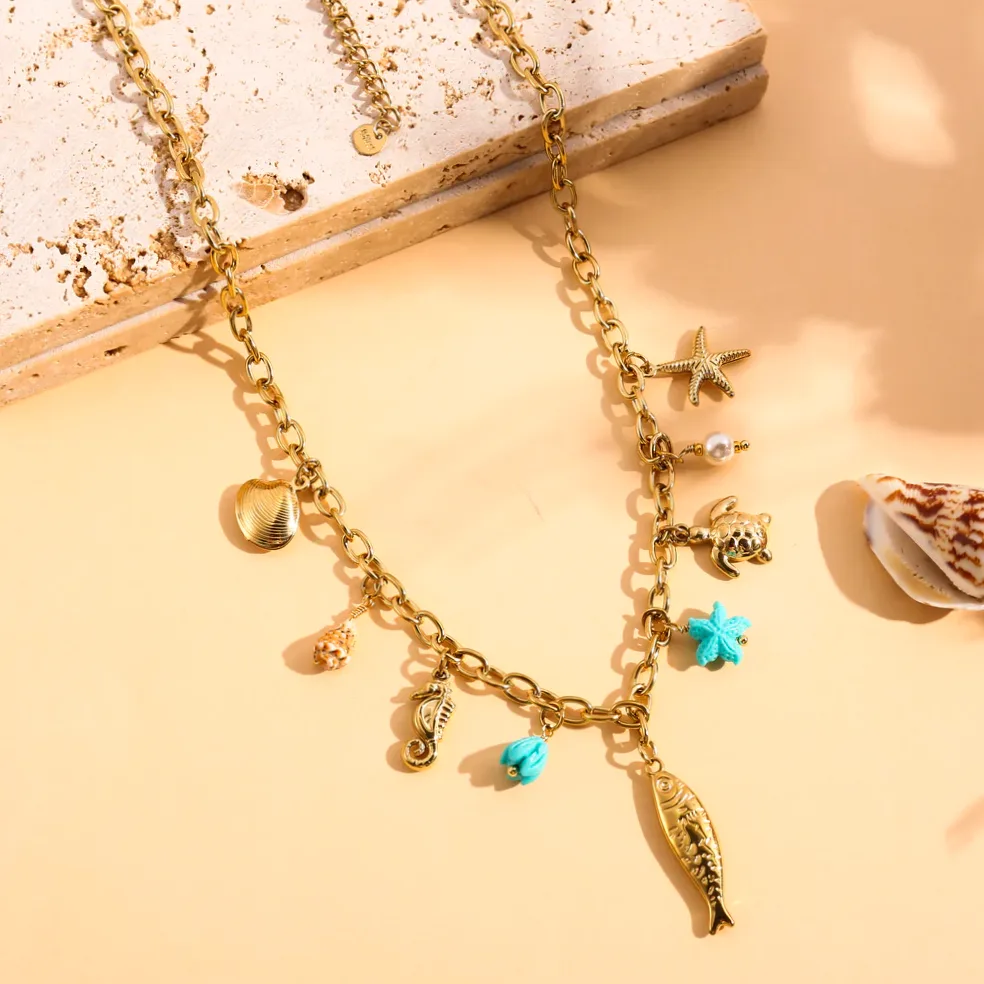 Detalhe do material e do acabamento — Colar dourado com charms peixe e estrela do mar