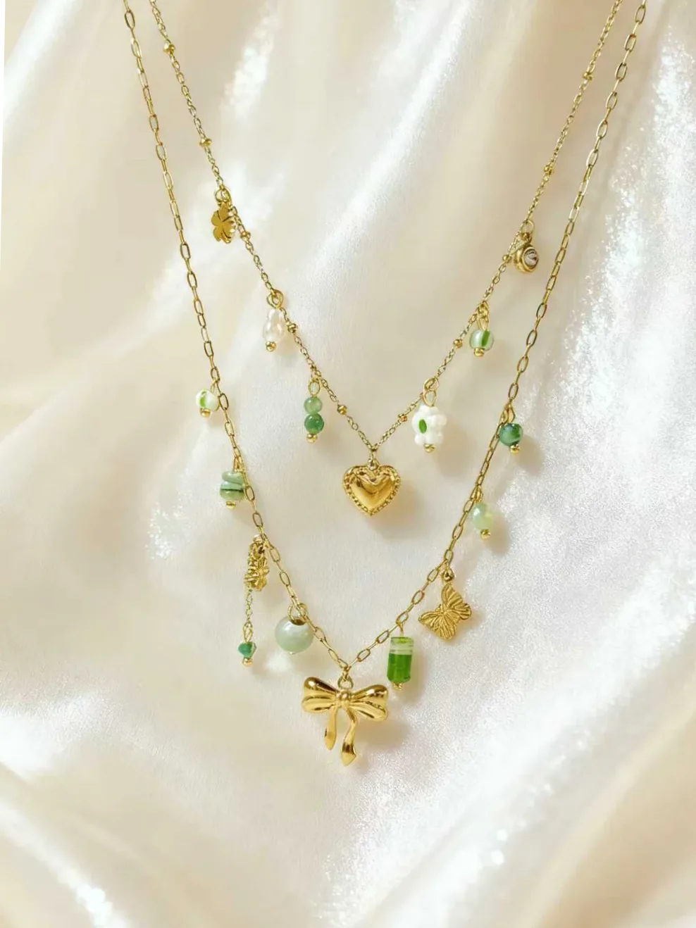 Detalle del material y acabado — Collar dorado doble charms lazo y perlas verdes