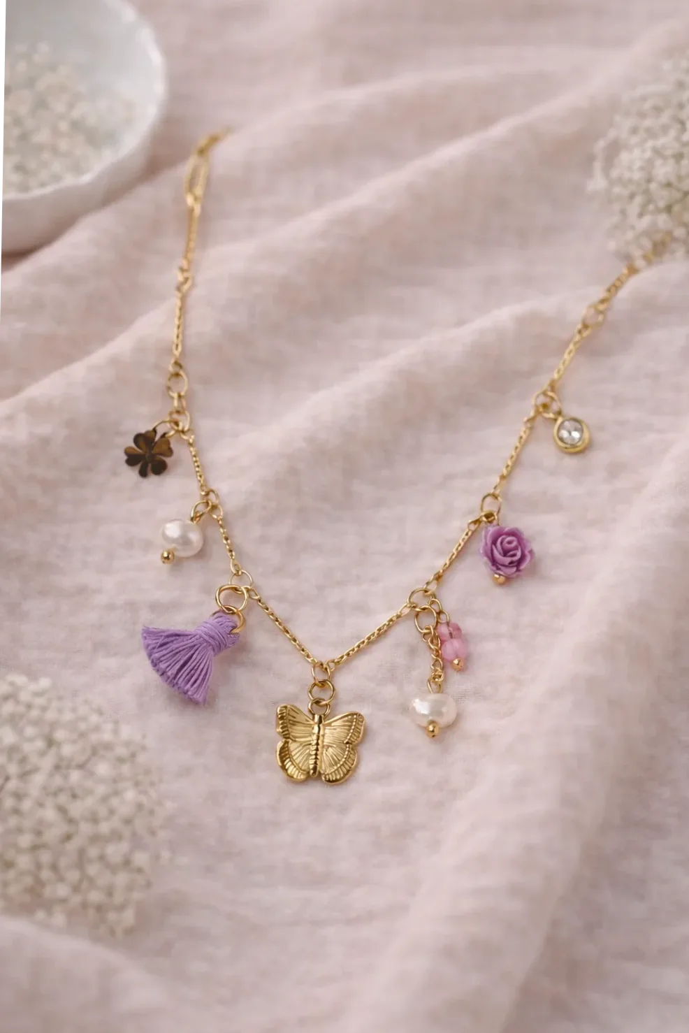 Detalle del material y acabado — Collar dorado fino charms mariposa y flores violetas