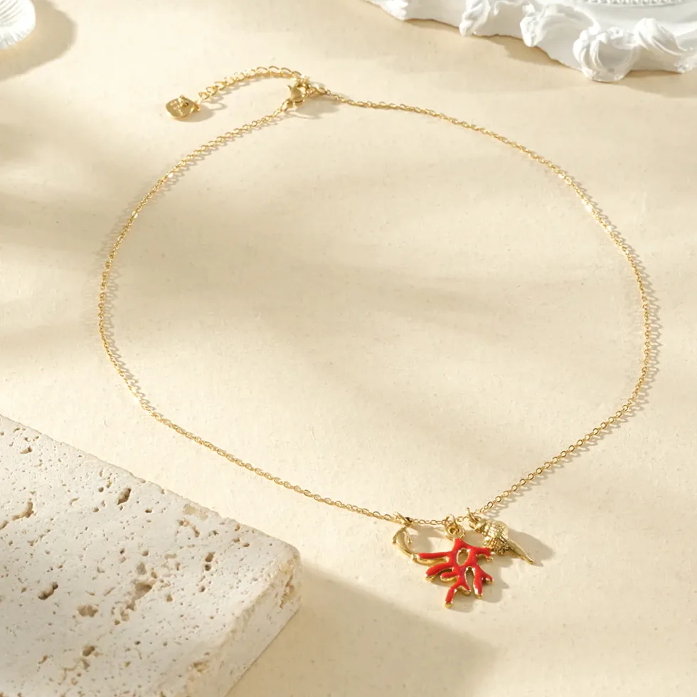 Collana dorata sottile pendenti corallo rosso e delfino indossato al collo